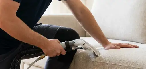 Professional upholstery cleaner deep-cleaning a fabric sofa with a handheld extraction tool, Oklahoma City, OK.